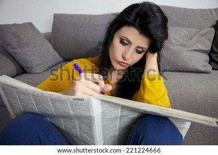 young woman looking for a job on newspaper with no success