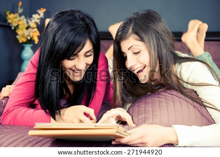 Cute young women smiling reading from social network on tablet