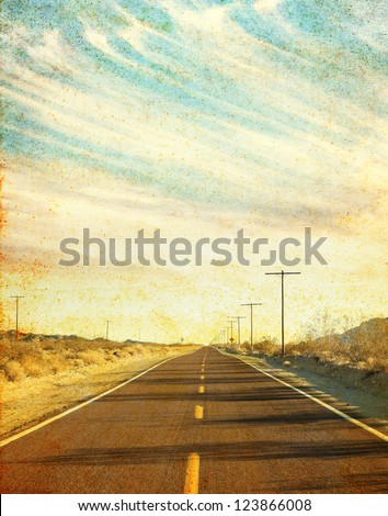 An empty desert road in Arizona\'s Mojave desert with grunge stains and spots.  Image has a distinct paper texture visible at 100%.