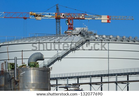 Cranes behind a big silo on an industrial construction site of a bio gas plant.