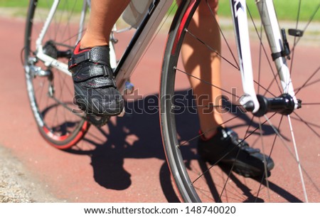 Close-up of female cyclist standing with her road racing bike. Shallow D.O.F.