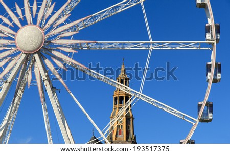 Ferris wheel and the \'Aa kerk\' on a beautiful day at the fair ground in Groningen, Netherlands.