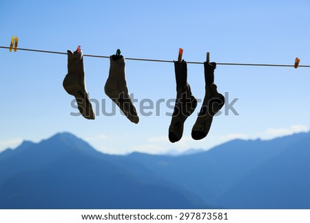 Two pair of socks drying on a clothes line during an adventurous hike in the mountains.