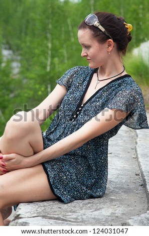 Young woman in dress sitting on a rock