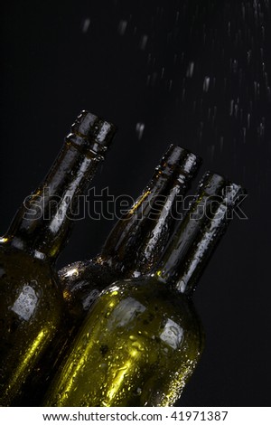 Bottle and drops of a condensate on a black background