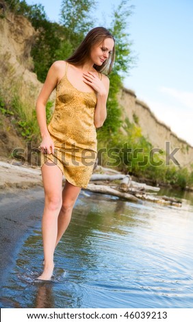 beautiful girl in wet dress goes on shore