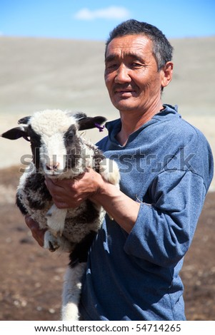 The adult man the shepherd carries on hands of a small lamb