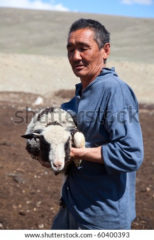 The adult man the shepherd carries on hands of a small lamb