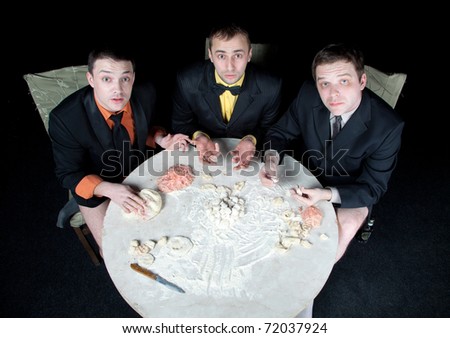 three men at a round table made dumplings