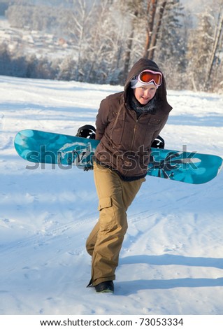 Woman with snowboard climbs up the hill