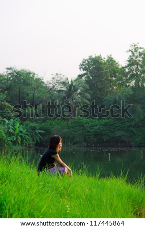 Cute Thai girl is letting her mind flow across the river bank in the rural area of Thailand.