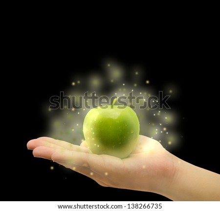 Magic apple on the man or woman hand palm with twinkle star light power in black isolated background. It is a magical food source of vitamin, fiber, and nutrition for anti aging.