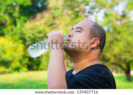An Asian bald head guy is pouring water into his mouth