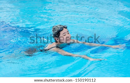 An Asian Thai girl in swimsuit is swimming in the blue clean water of the swimming pool for exercise