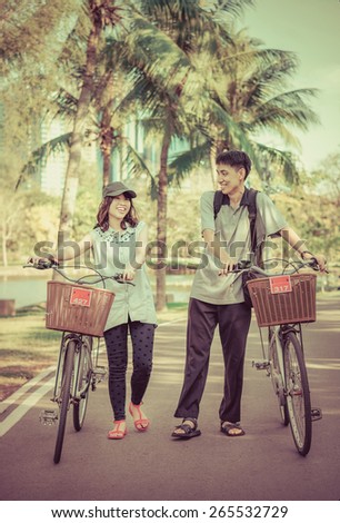 A friend couple are walking and chatting with bicycle in the park in vintage color
