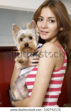 Cute young brunette girl with her Yorkshire terrier puppy lying on sofa