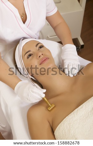 Young brunette woman receiving laser therapy. Spa studio shot