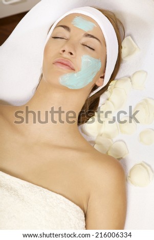 young adult brunette woman getting beauty skin mask treatment on her face with brush