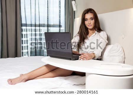 Young adult beauty attractive sexy and sensuality happy pretty brunette businesswoman using laptop while lying on bed in hotel room