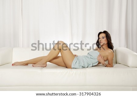 Portrait of a beautiful young adult attractive sexy and sensuality pretty female brunette woman posing in blue blanket on the white couch