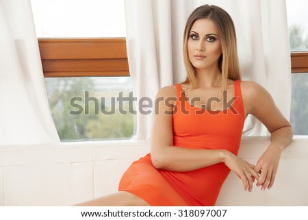 Portrait of a beautiful attractive sensuality and sexy young adult pretty brunette woman wearing elegance fashionable red dress in white couch