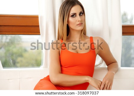 Portrait of a beautiful attractive sensuality and sexy young adult pretty brunette woman wearing elegance fashionable red dress in white couch
