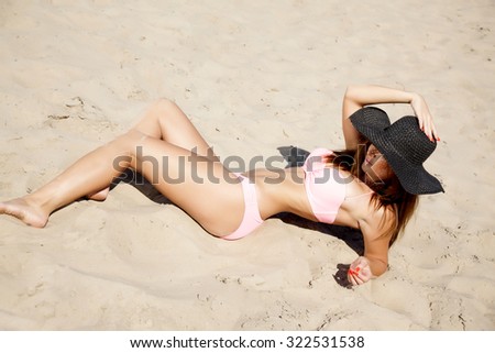 Portrait of a young adult beautiful brunette attractive sexy and sensuality pretty brunette woman in pink bikini and black hat on the summer sunlight beach
