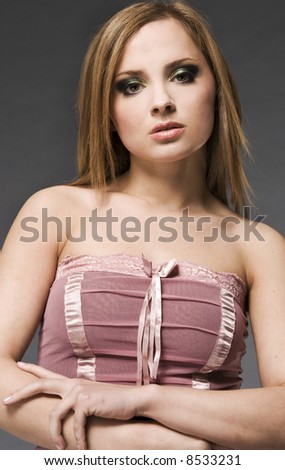 portrait of blonde girl wearing pink blouse on grey background