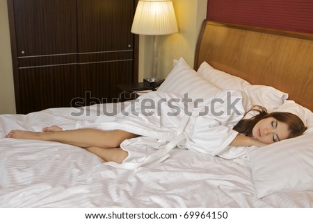 Above view of young beautiful woman sleeping in bed covered with white silky sheet