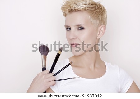 Attractive blonde Make-up artist holding brushes