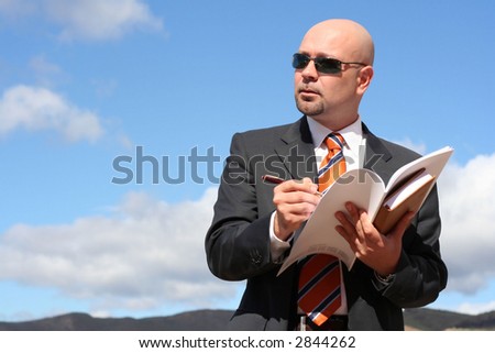 Businessman writing at his agenda and thinking about business\