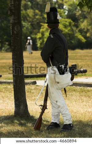 Soldier from a War of 1812 re-enactment turned to watch a pretty girl across the field.