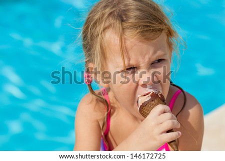 little girl eating ice cream at the pool