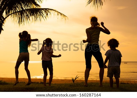 Happy family dancing the beach on the dawn time