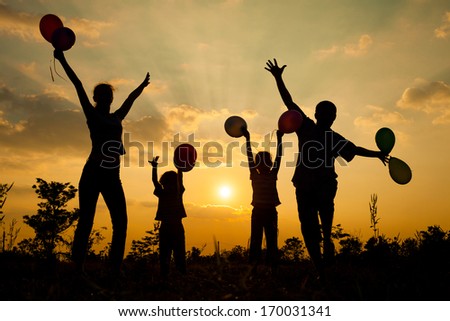 Happy  family dancing with balloons on the  road in the  sunset time. Evening party on the nature