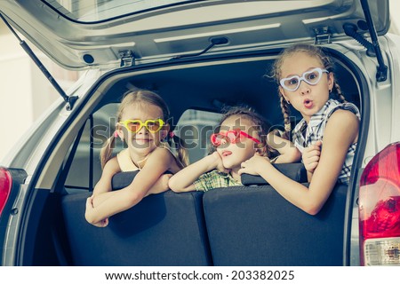 Brother and sisters  sitting in the car near house at the day time