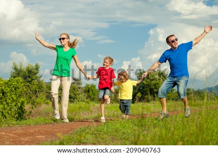 Happy family jumping on the road at the day time. Concept of friendly family.