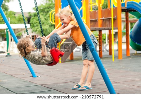 Two happy children on the playground at the day time. Concept brother and sister forever.