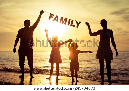 Happy family standing on the beach at the sunset time. Parents hold in the hands  inscription \