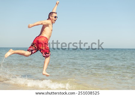 Happy man jumping on the beach at the day time