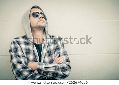 Portrait of a one sad man in sunglasses sitting outdoors near the house at the day time