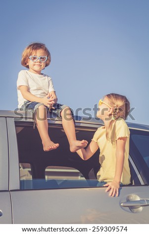 Happy brother and sister are sitting in the car at the day time