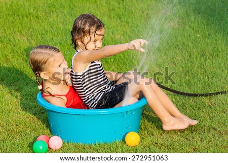 brother and sister playing with water near a house at the day time