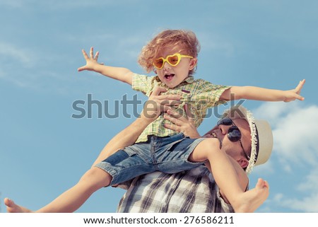 Dad and son in sunglasses playing near a house at the day time. Concept of friendly family.