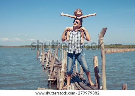 Father and son resting on the bridge in the sea at the day time. Concept of friendly family.