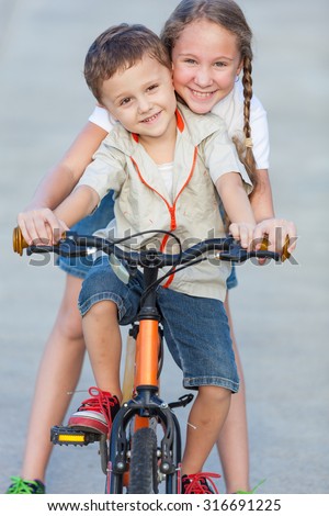 Happy kids with bike standing on the road at the day time. Concept Brother And Sister Together Forever