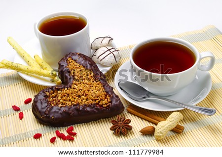 Two tea and cookies and cake in the shape of heart