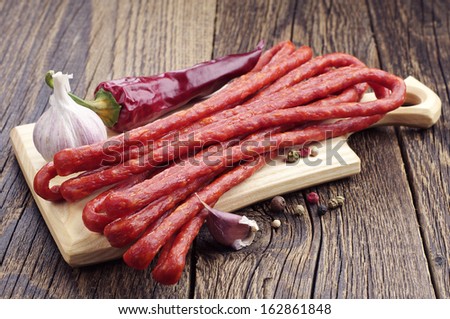 Long thin dry sausage, pepper and garlic on old wooden table