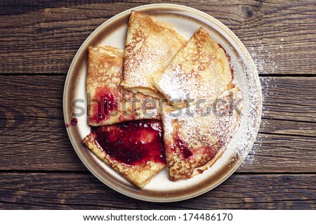 Fried pancakes with jam on vintage wooden background. Top view