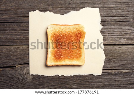 Toast bread on torn paper on vintage wooden background. Top view